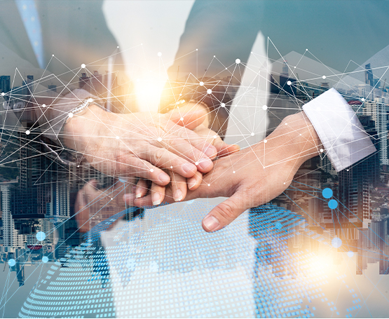 Several hands stacked together in a gesture of teamwork, with a cityscape in the background and digital network graphics overlaying the image, symbolizing collaboration and technology in business.